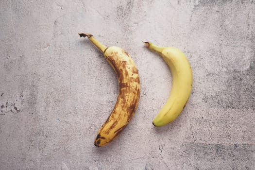 comparing rotten banana with a ripe banana on a white background