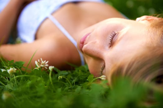 Spring, sleeping and relax with woman on grass in nature for calm, park and peace. Holiday, flowers and field with face of female person lying in countryside meadow for summer, vacation and wellness