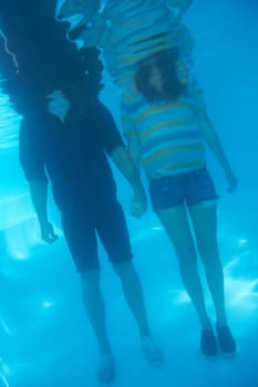 Holding hands, swimming and a couple underwater for love, support or trust in relationship. Body, standing and a man and woman with care, affection and in a pool together for emotion or unity.