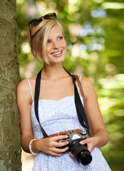 Smile, nature and photographer with woman in forest for relax, memory and travel photography. Summer, trees and adventure with female person with camera for vacation, holiday or environmental tourism