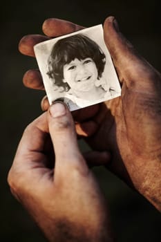 Hands, holding picture of kid and portrait, nostalgia or remember memory of family or child isolated on black background in studio. Closeup, photo of boy and dirty fingers of homeless man in poverty