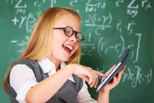 Girl, calculator and happy for education, learning and problem solving or solution on chalkboard. Smart student, kid or child with glasses and excited for school, typing numbers and math in classroom