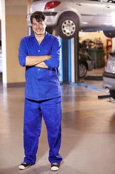 Professional, portrait and mechanic with arms crossed in a workshop for pride in a car. Smile, working and man in a garage for work, maintenance or building a vehicle for transportation or inspection