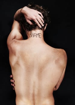 Back, shame tattoo and nude man in studio isolated on a black background. Rear view, regret and body of person embarrassed at mistake, fail and abuse crisis, depression and mental health challenge