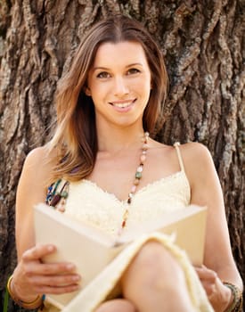 Woman, smile and reading outdoors to relax, peace and calm in nature for travel adventure in New York. Happy female person, portrait and break by tree, literature and fiction in park, story or novel