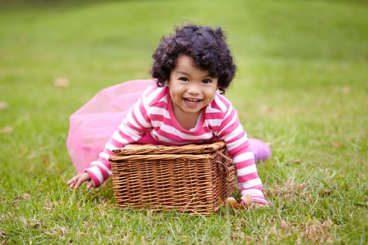 Portrait, happy child and basket for picnic in park with laugh, smile and fun. Girl. curly hair and natural in pink tutu for imagine, game or whimsical activity for growth, wellness or development