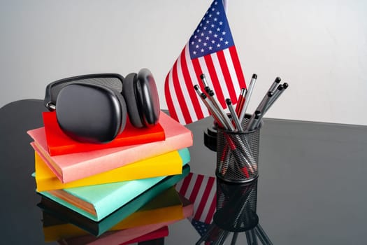 USA flag with pile of colorful books on black table