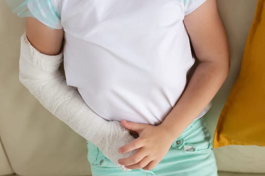 Close-up child girl with a cast on a broken wrist or arm smiling at home