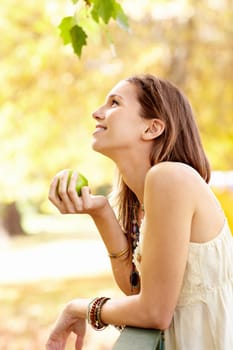 Apple, park and woman with thinking in nature eating fruit for health with smile and happiness on a farm. Wellness, happy and young person on a diet for nutrition and summer of organic agriculture