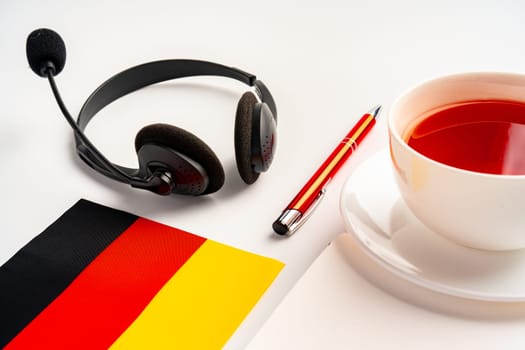 Notepad with German flag and headphones on white background. German language audio courses educational concept