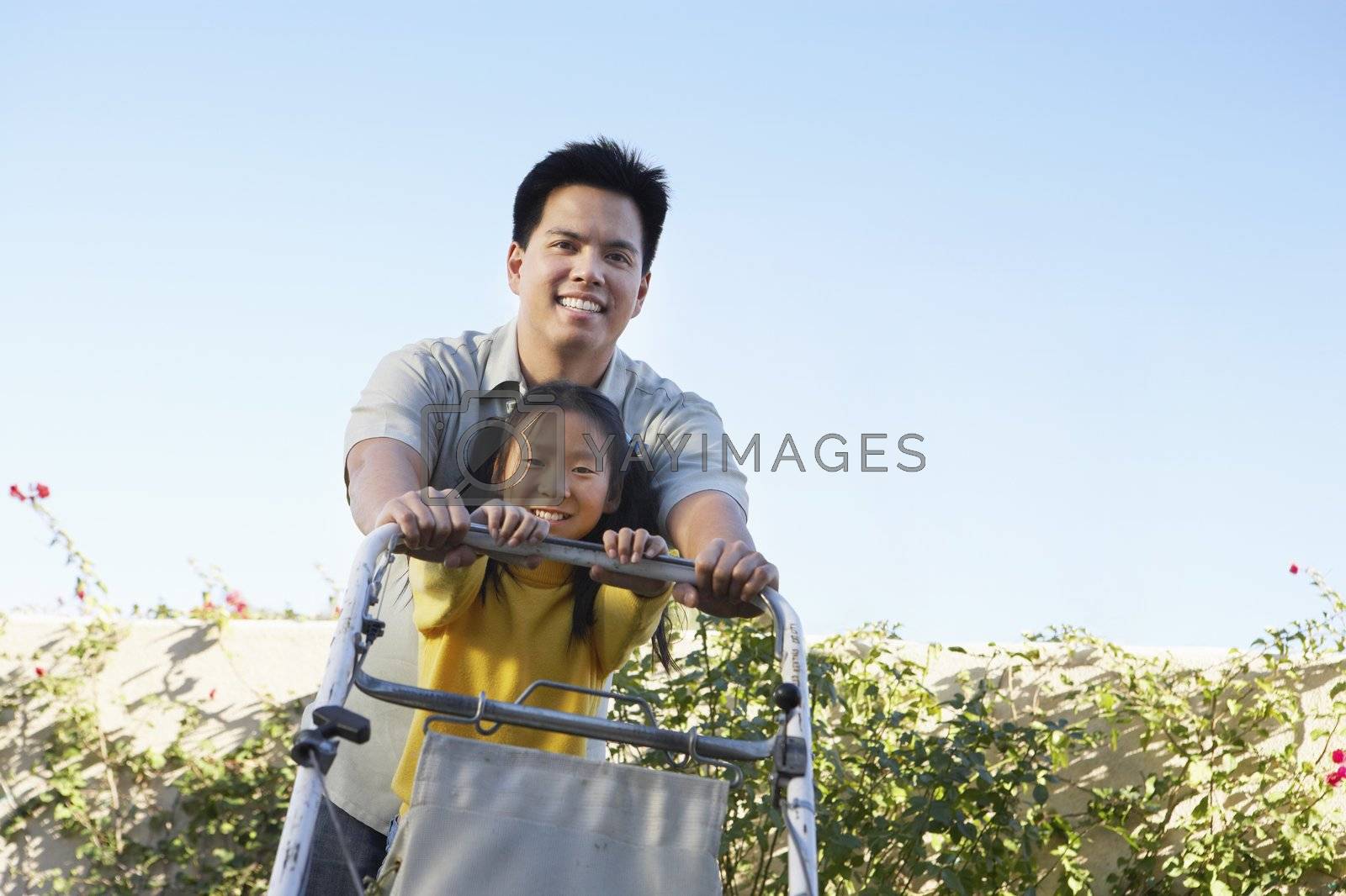 Royalty free image of Girl Helping Father Mow the Lawn by moodboard