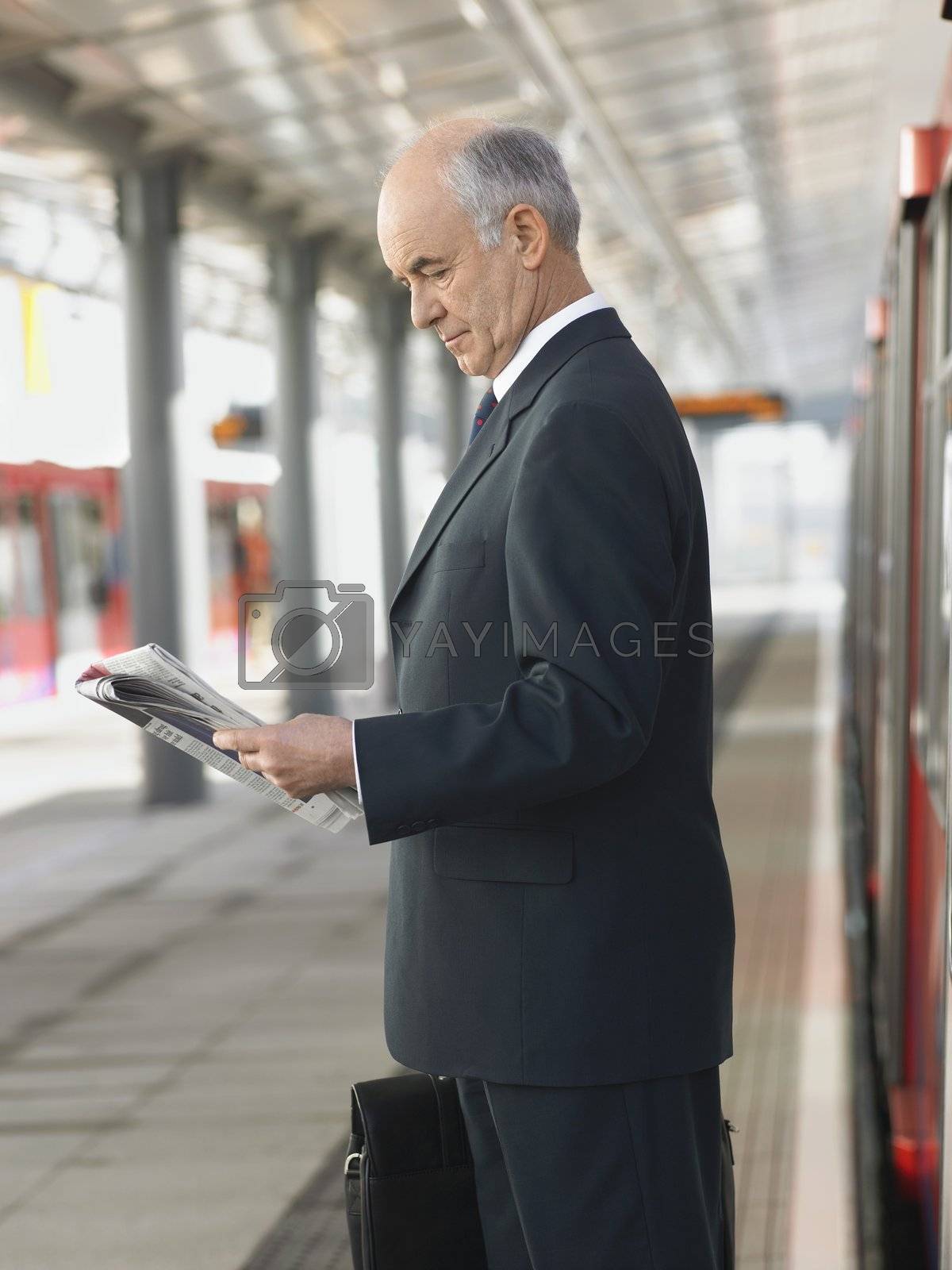 Royalty free image of Businessman Reading Newspaper at Train Station by moodboard