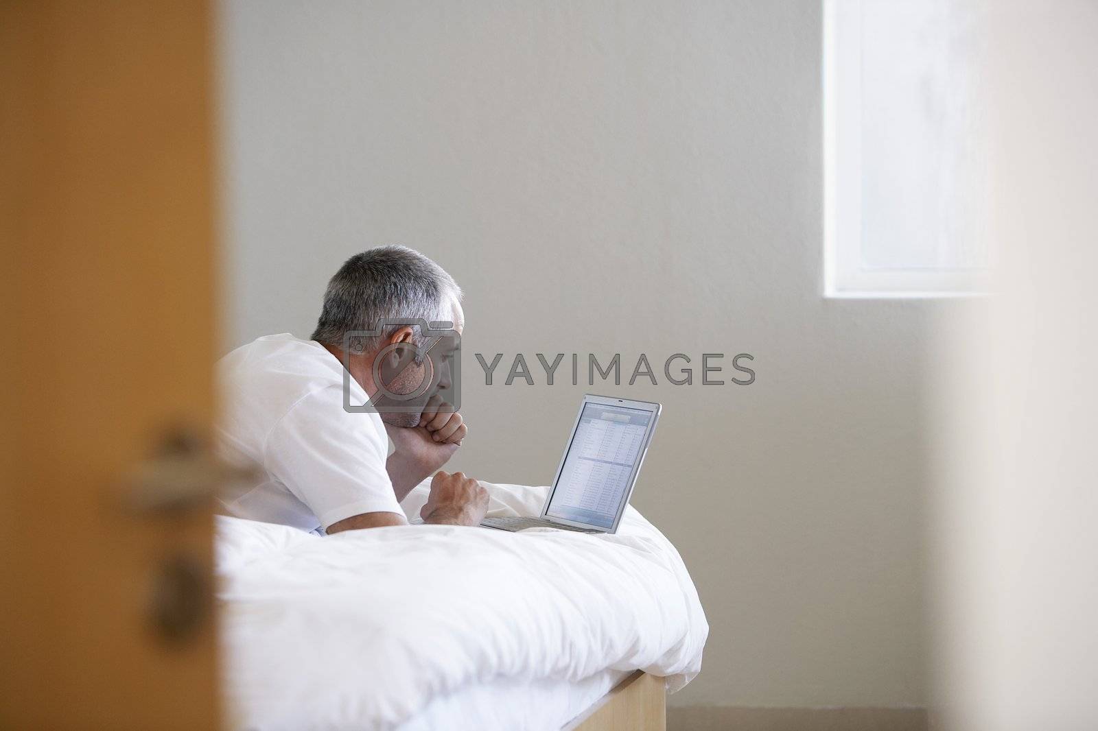 Royalty free image of Man Using Laptop on Bed by moodboard