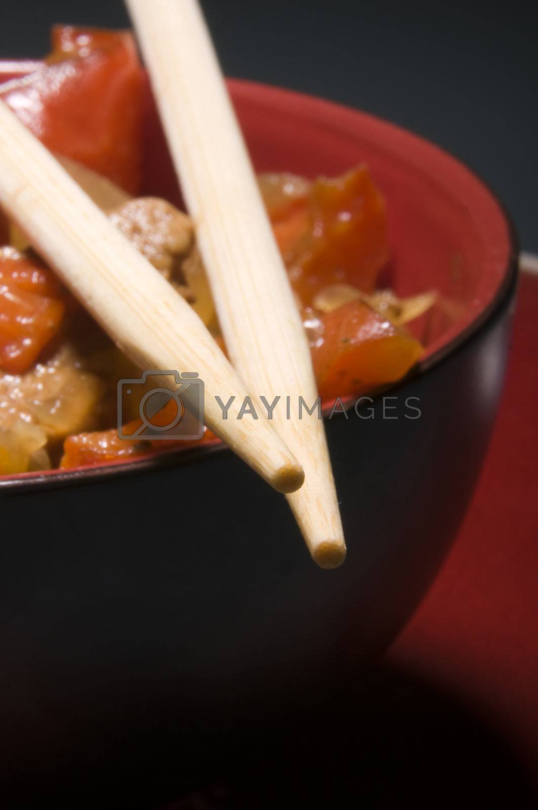 Red bowl with meat and vegetables and chopsticks