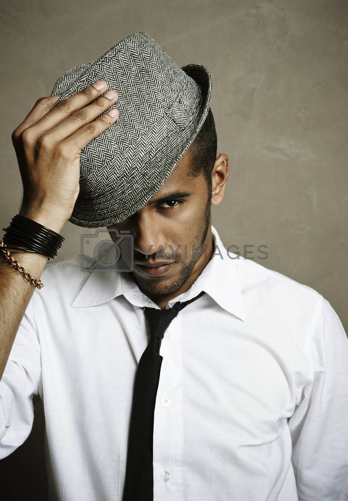 Male model stares at camera with hand on hat
