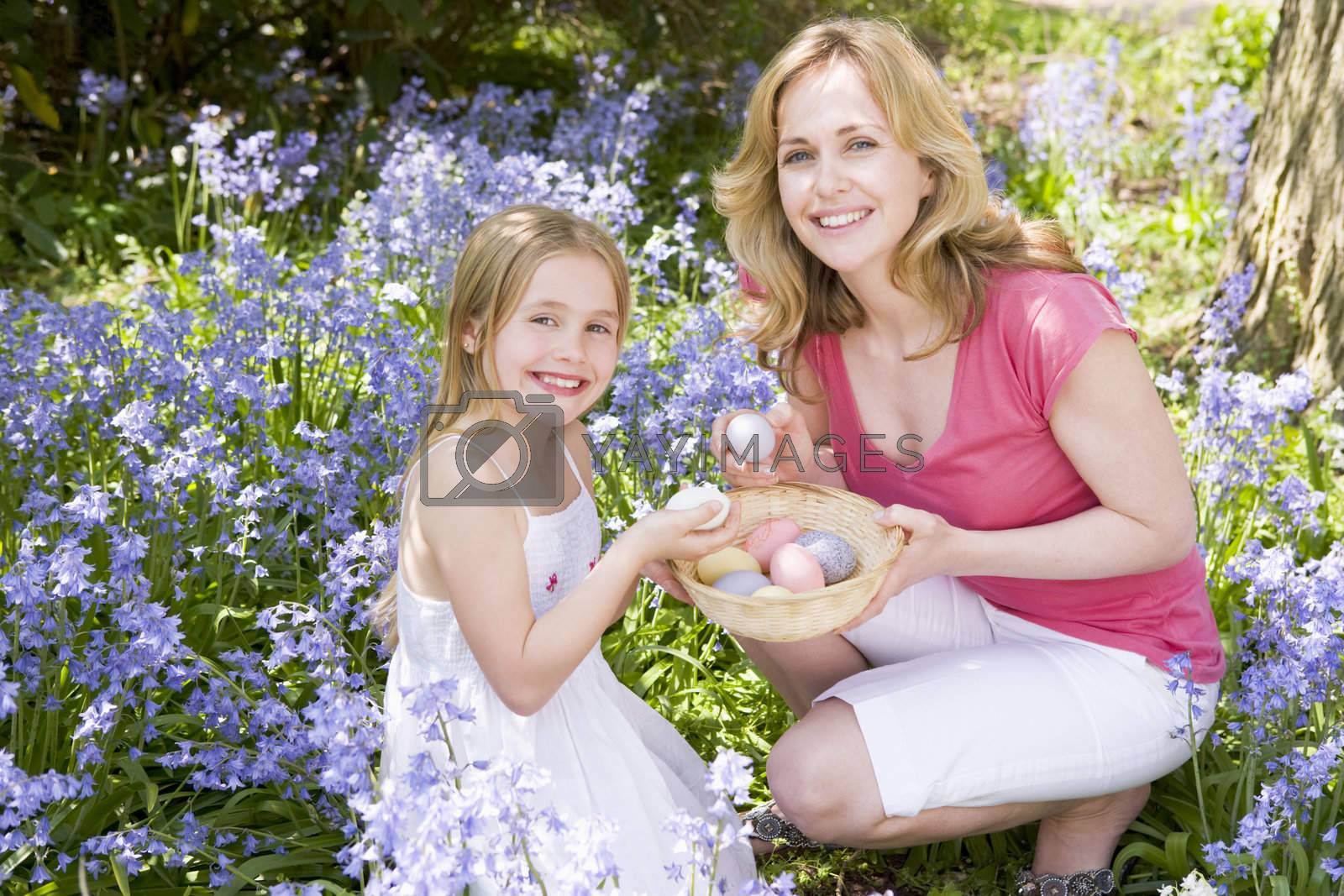 Royalty free image of Mother and daughter on Easter looking for eggs outdoors smiling by MonkeyBusiness