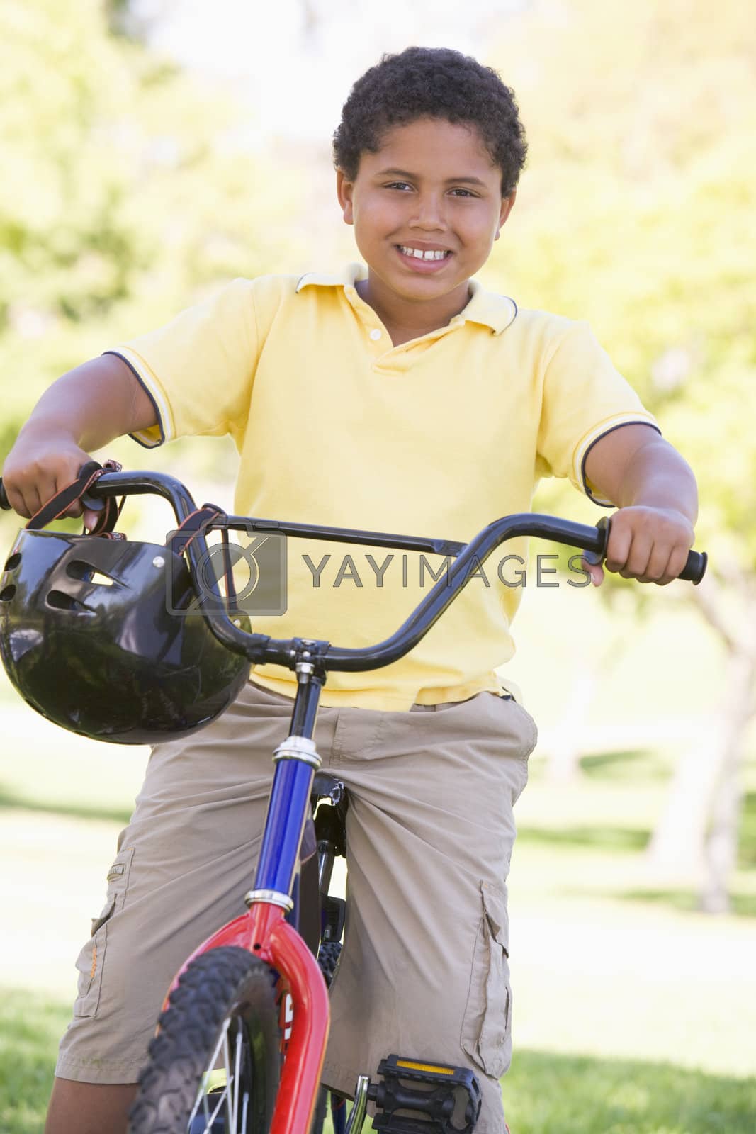 Royalty free image of Young boy on bicycle outdoors smiling by MonkeyBusiness
