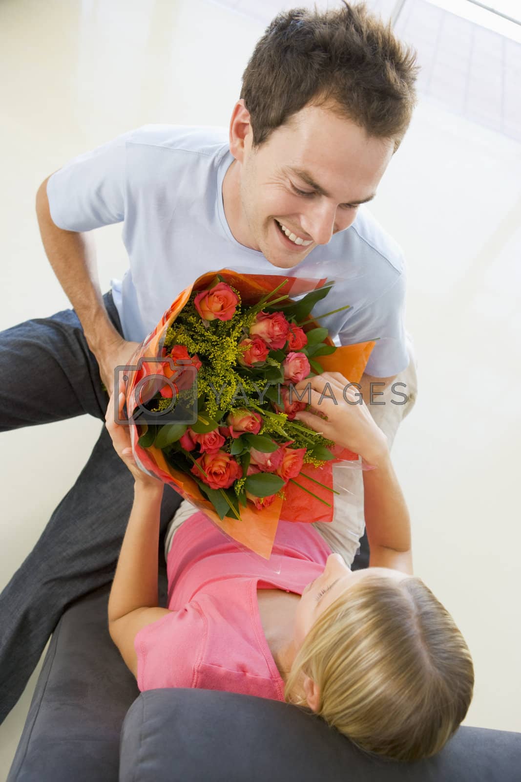 Royalty free image of Husband giving wife flowers and smiling by MonkeyBusiness