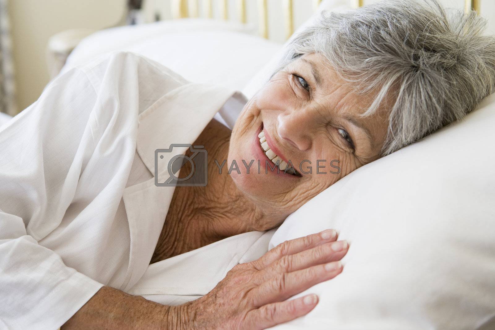 Royalty free image of Woman lying in bed smiling by MonkeyBusiness