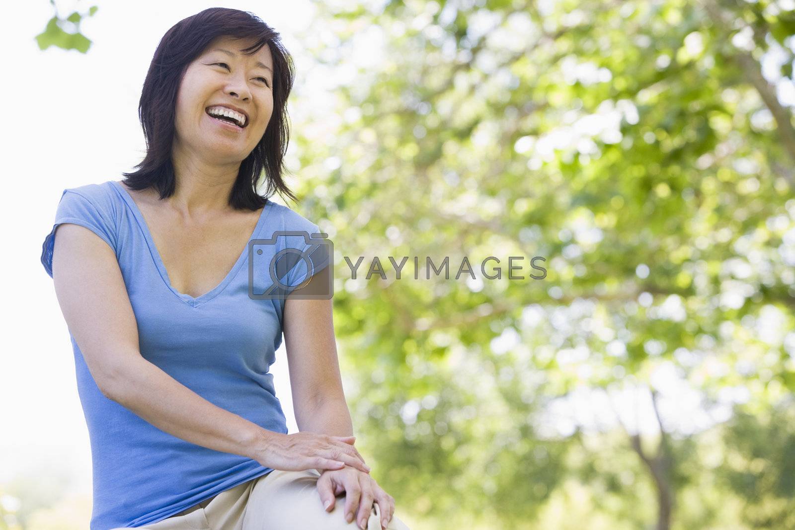 Royalty free image of Woman sitting outdoors smiling by MonkeyBusiness