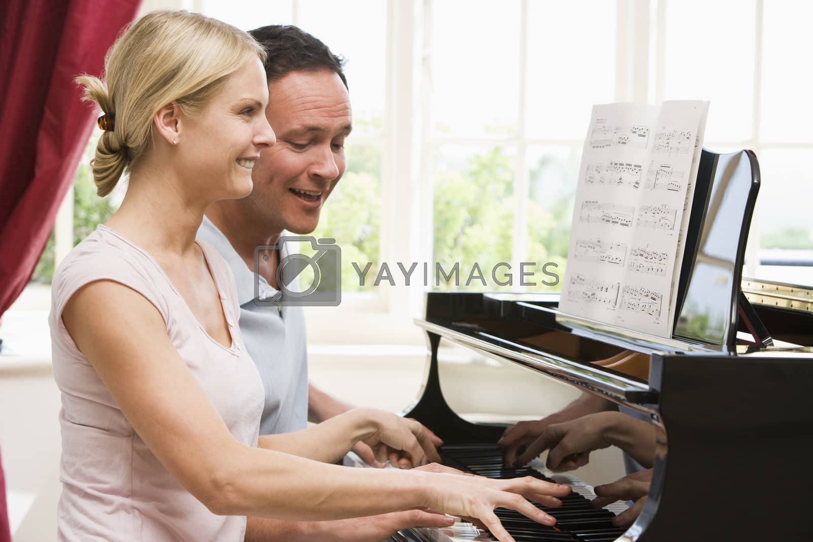 Royalty free image of Couple playing piano and smiling by MonkeyBusiness