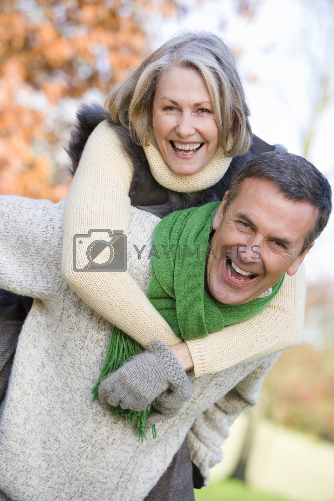 Royalty free image of Senior man outdoors piggybacking woman and smiling  by MonkeyBusiness