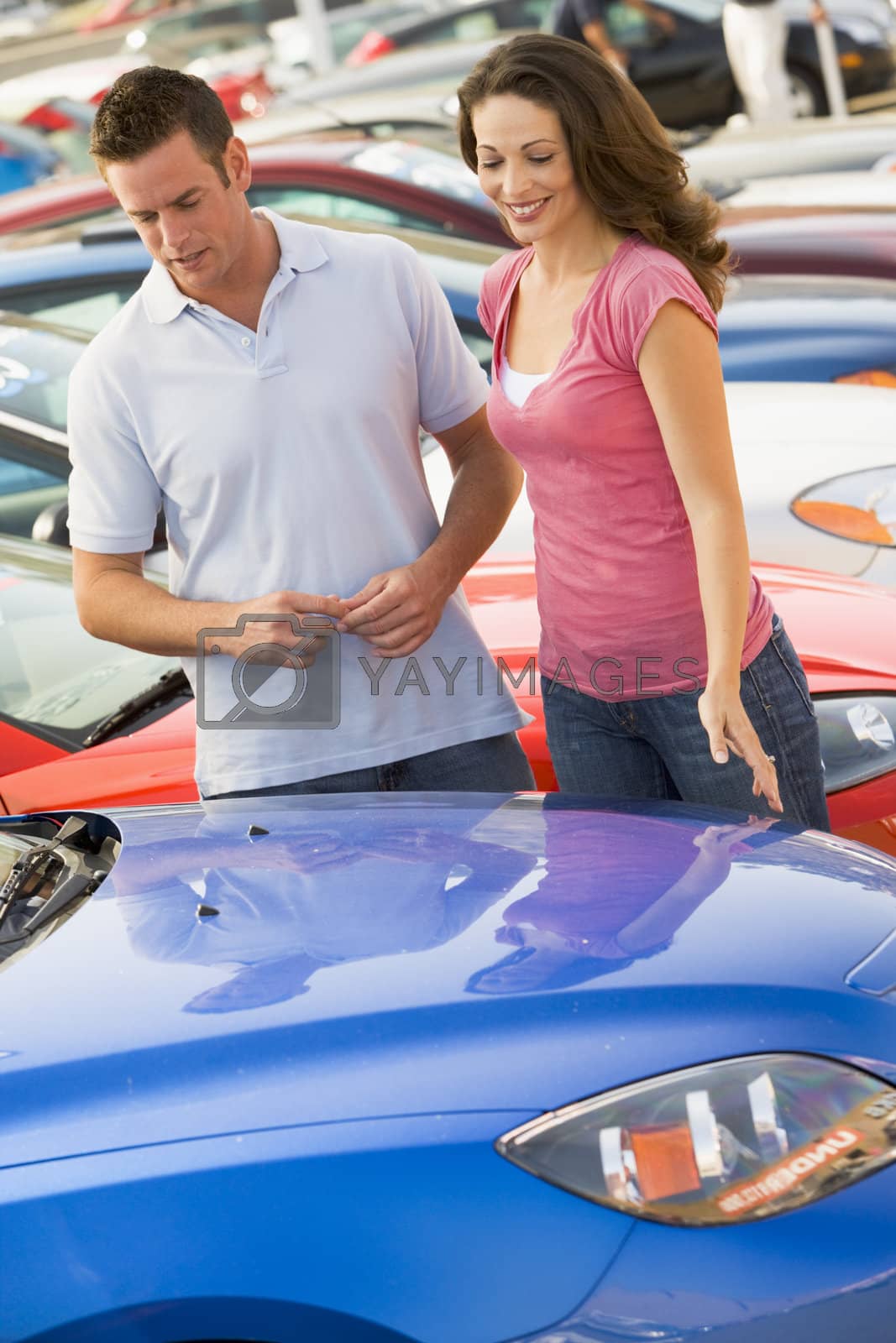 Royalty free image of Couple looking at new cars by MonkeyBusiness