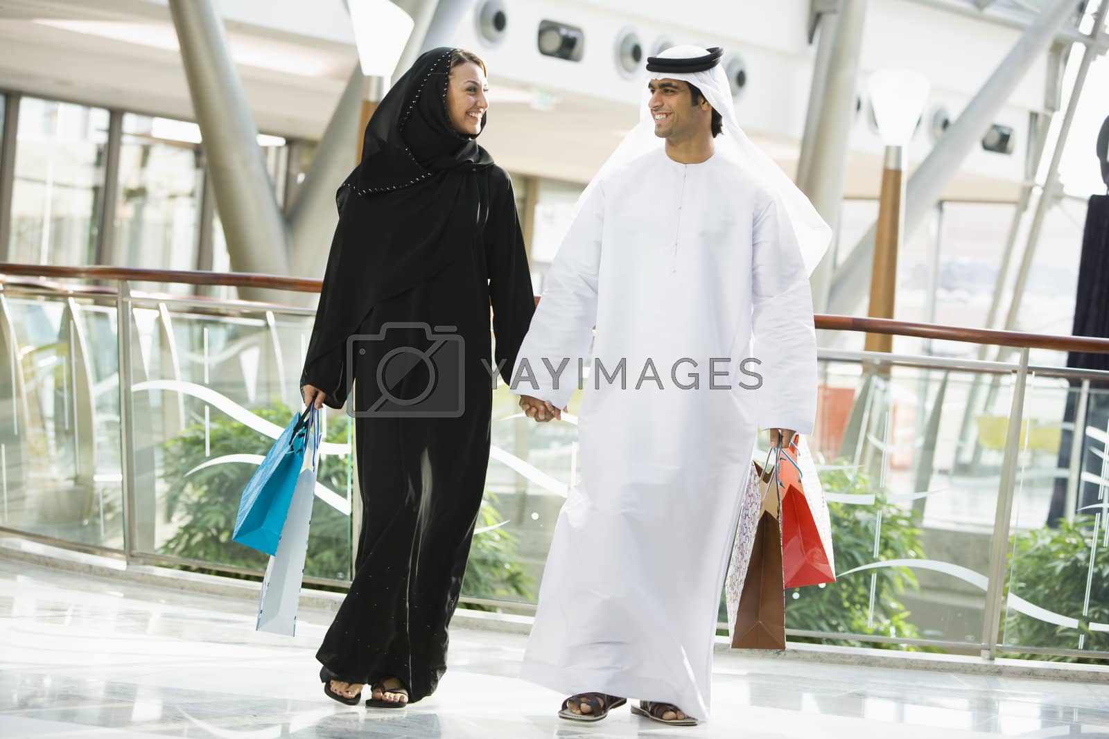 Royalty free image of Couple walking in mall holding hands and smiling (selective focus)  by MonkeyBusiness