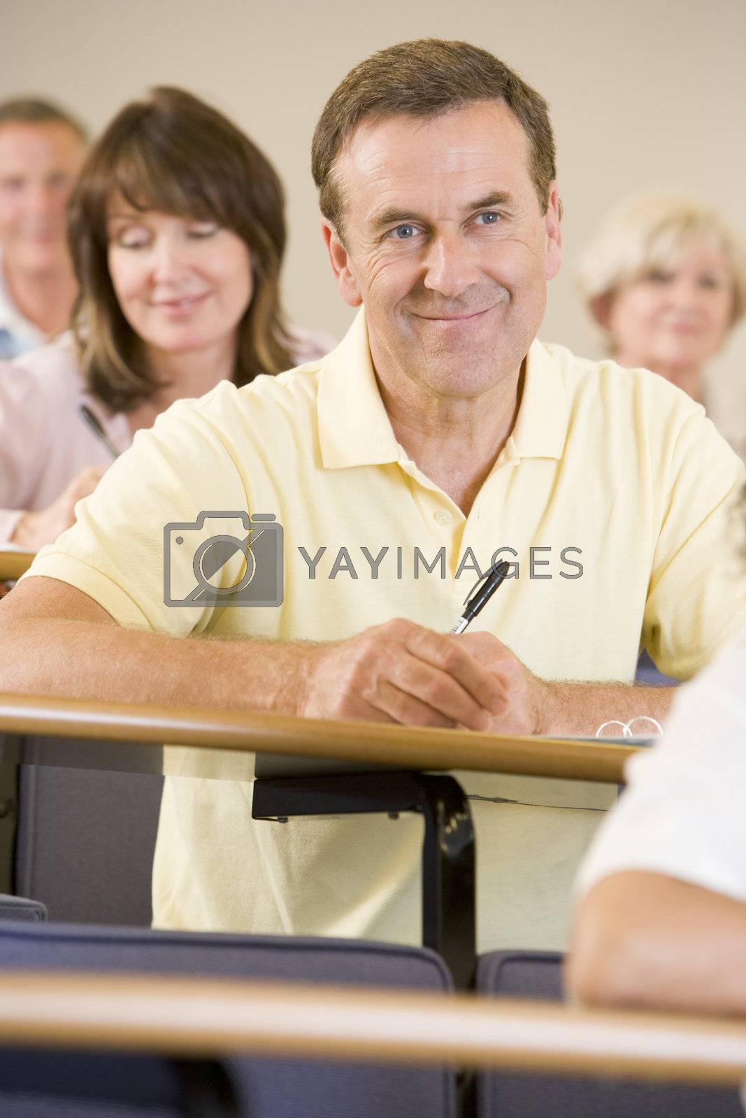 Royalty free image of Man sitting in adult classroom with students in background (selective focus) by MonkeyBusiness