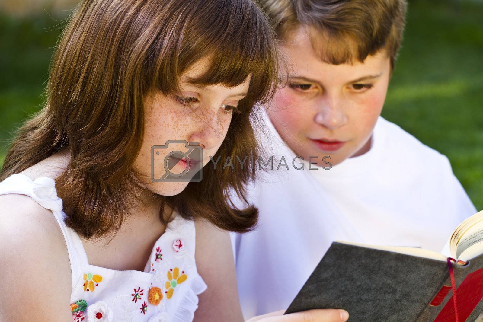 Royalty free image of Portrait of cute kids reading books in natural environment by FernandoCortes