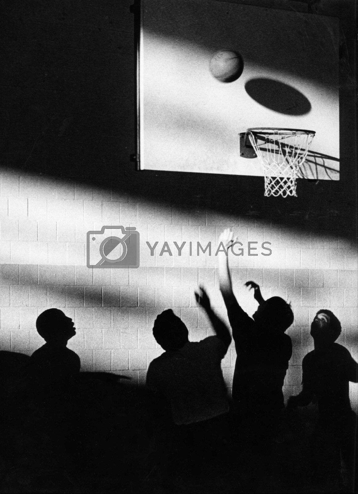 Royalty free image of Young men playing basketball with a silhuette creating an artistic look. by athomedad