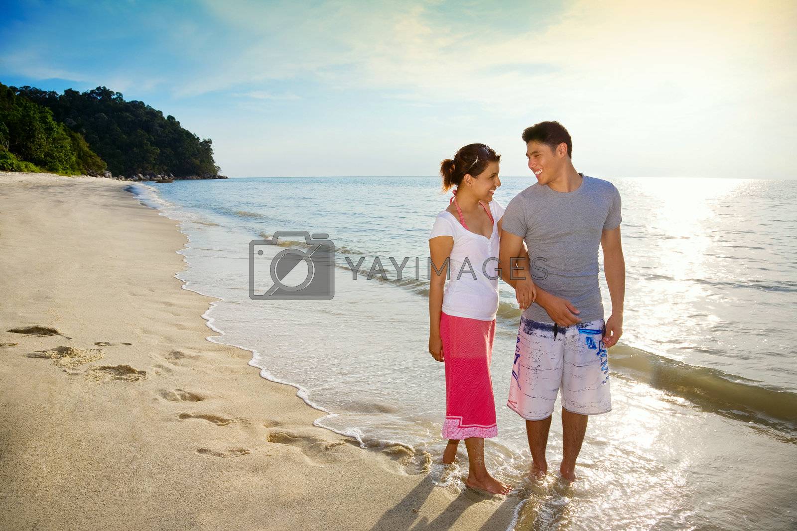 Royalty free image of happy couple walking along the beach by eyedear