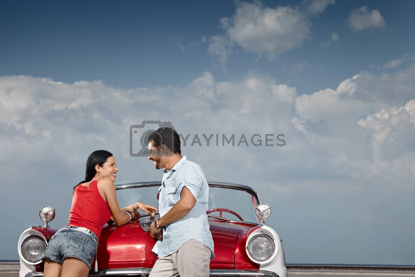 Royalty free image of man and beautiful woman leaning on cabriolet car by diego_cervo