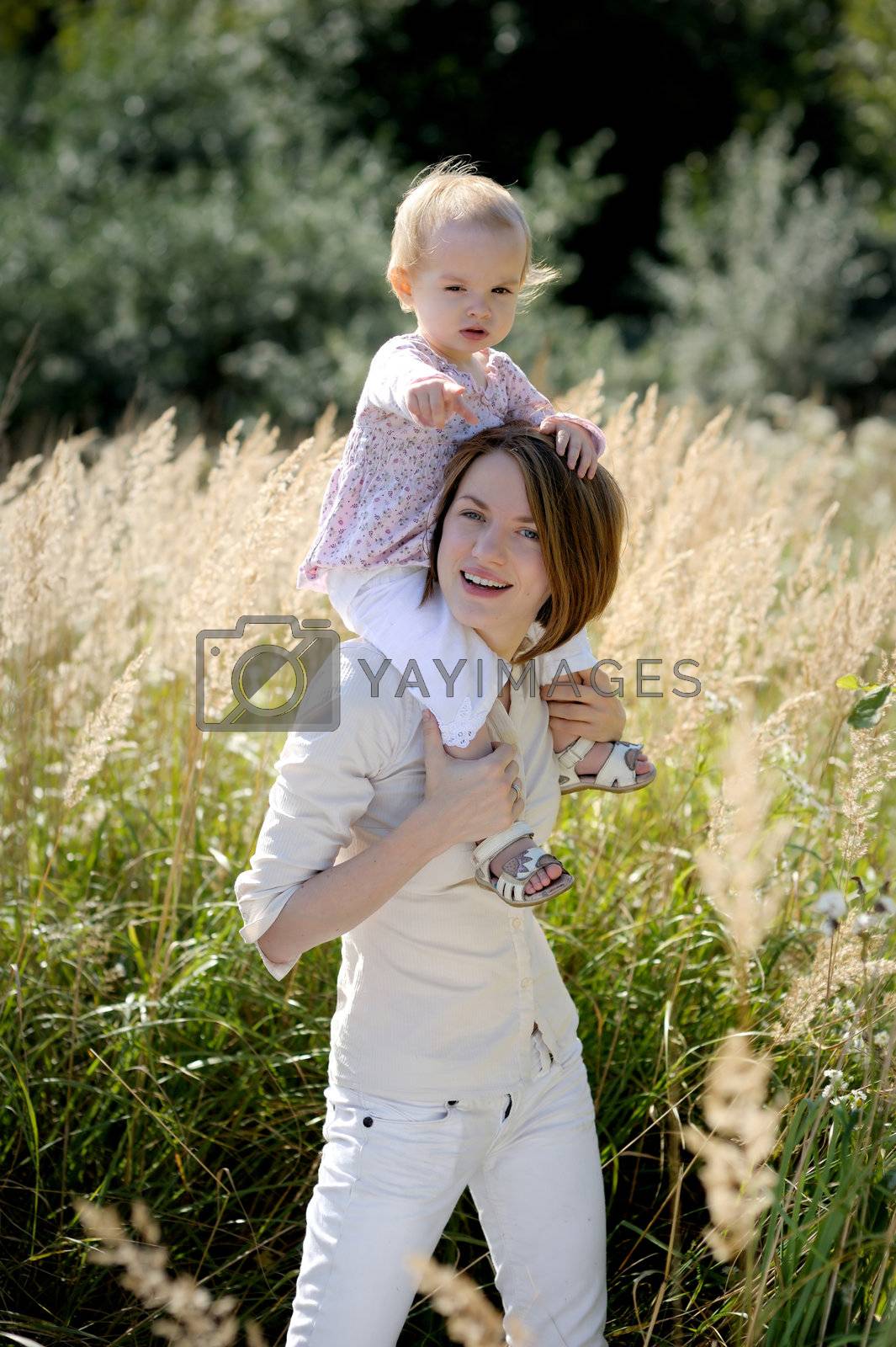 Royalty free image of Mother with a baby on her shoulders pointing at you by maximkabb
