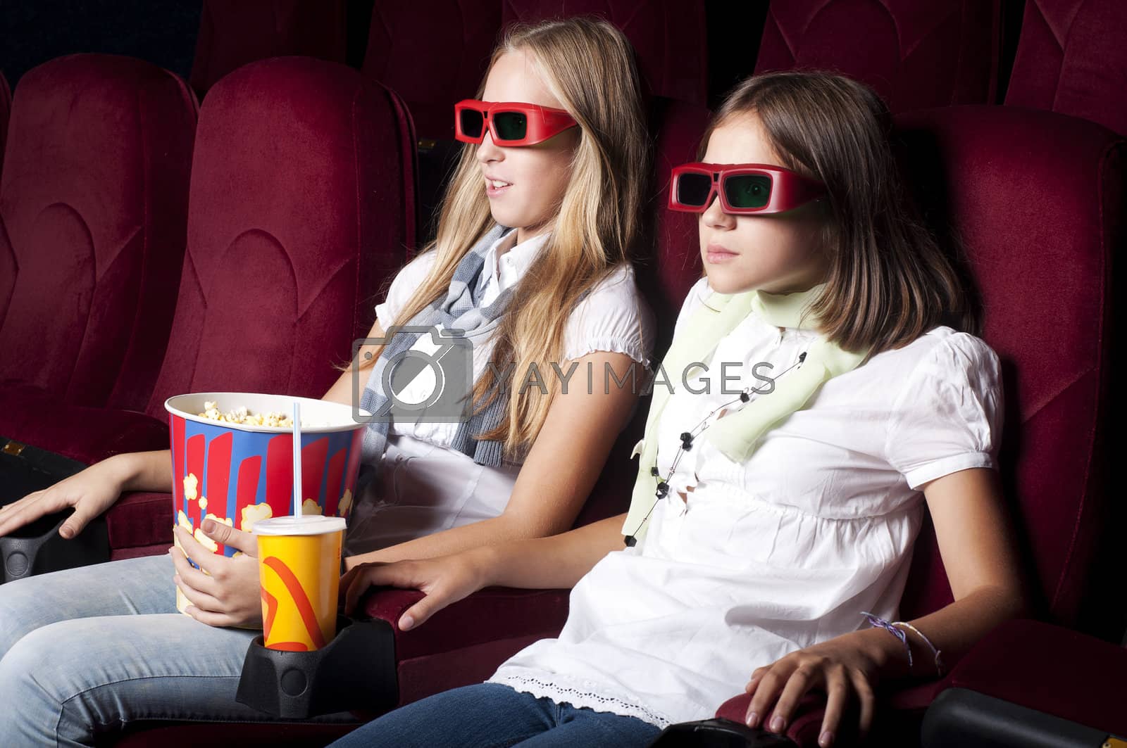 Royalty free image of two beautiful girls watching a movie at the cinema by adam121
