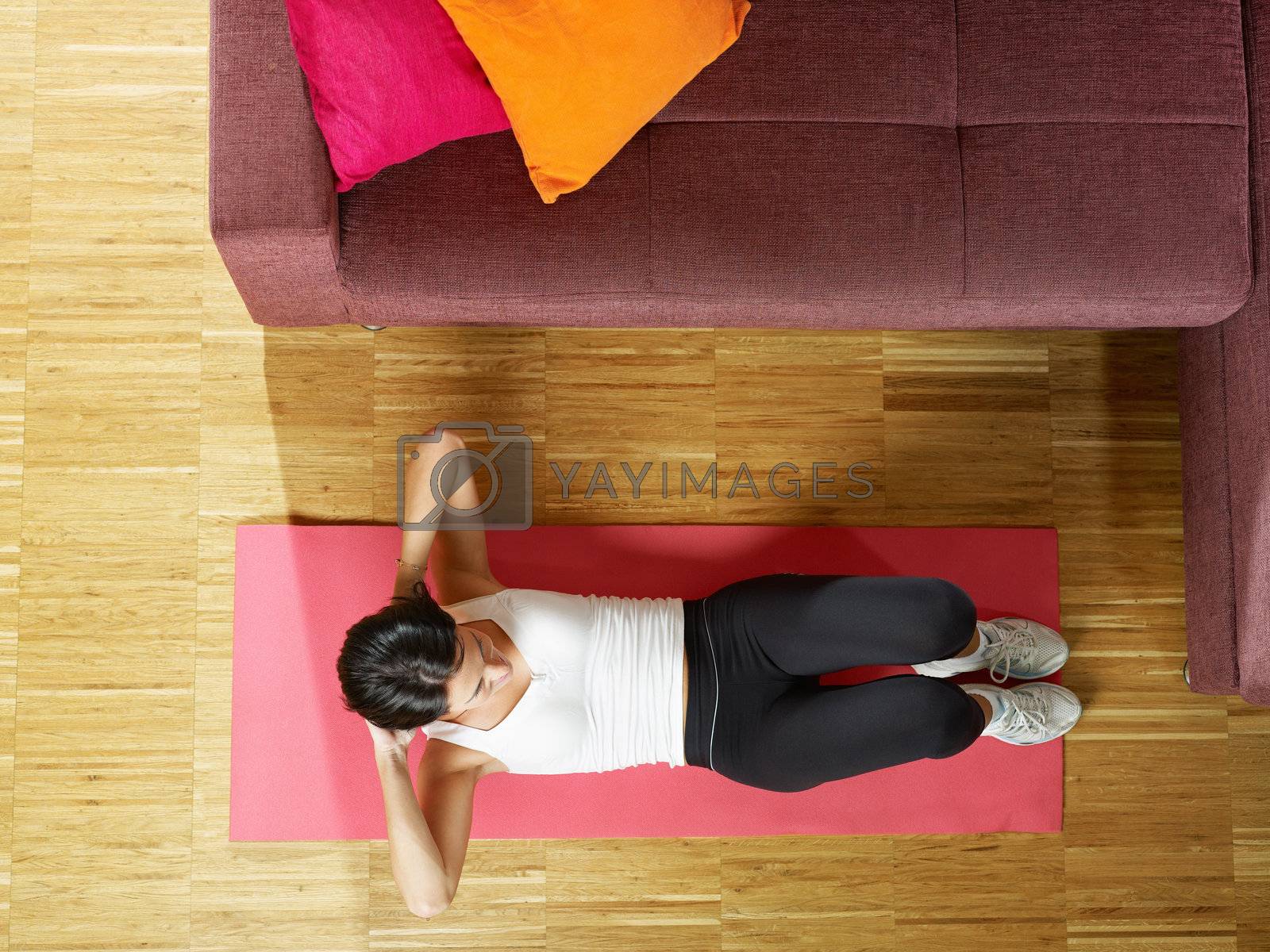 Royalty free image of woman doing abs exercise at home by diego_cervo