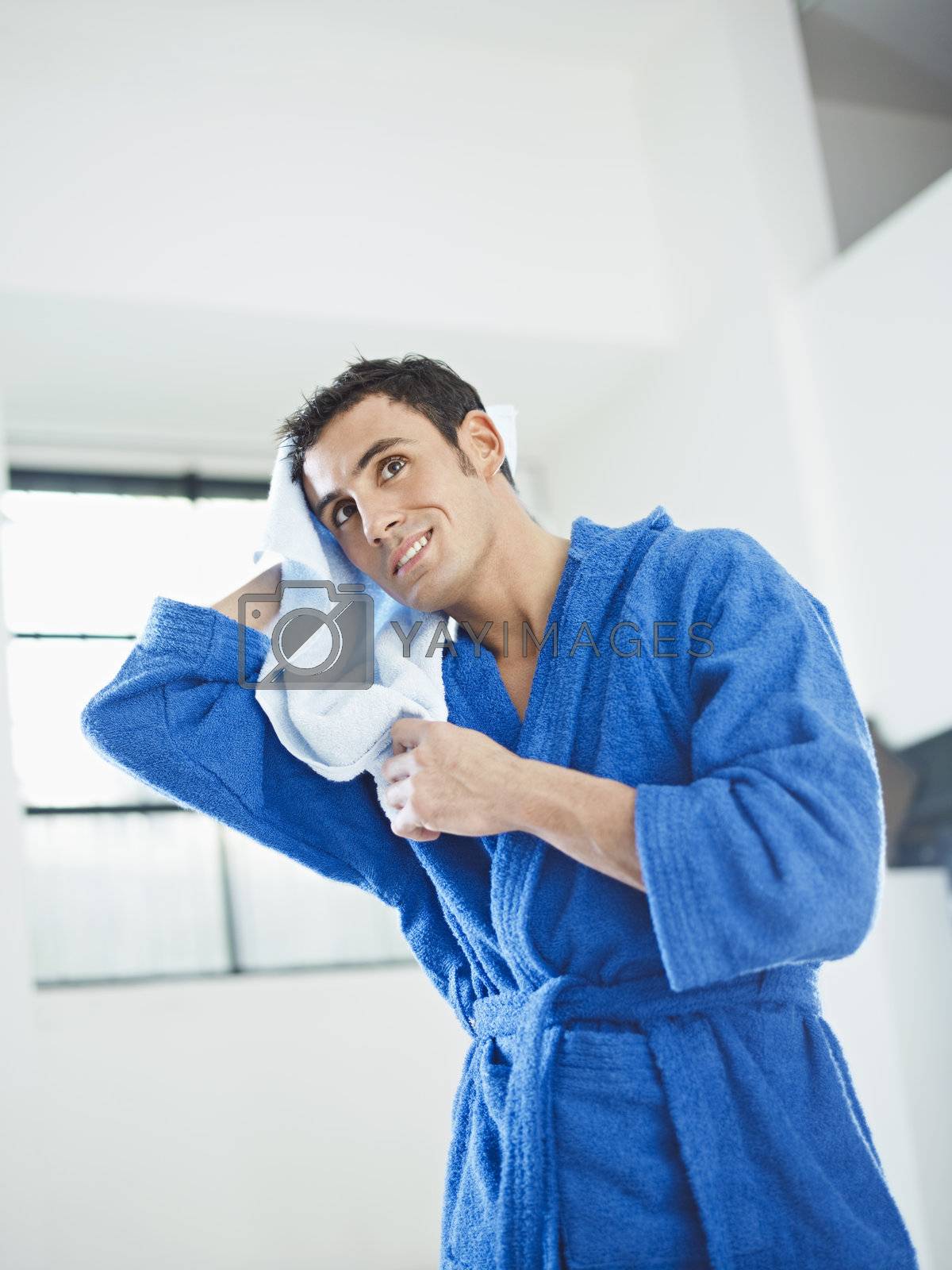 young caucasian man in blue bathrobe drying hair. Vertical shape, three quarter length, copy space