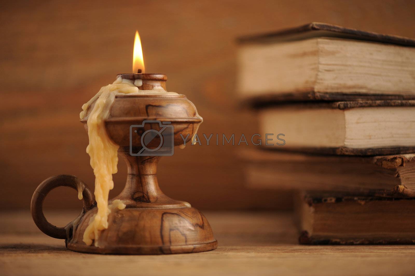 Royalty free image of old candle on a wooden table, old books in the background by stokkete