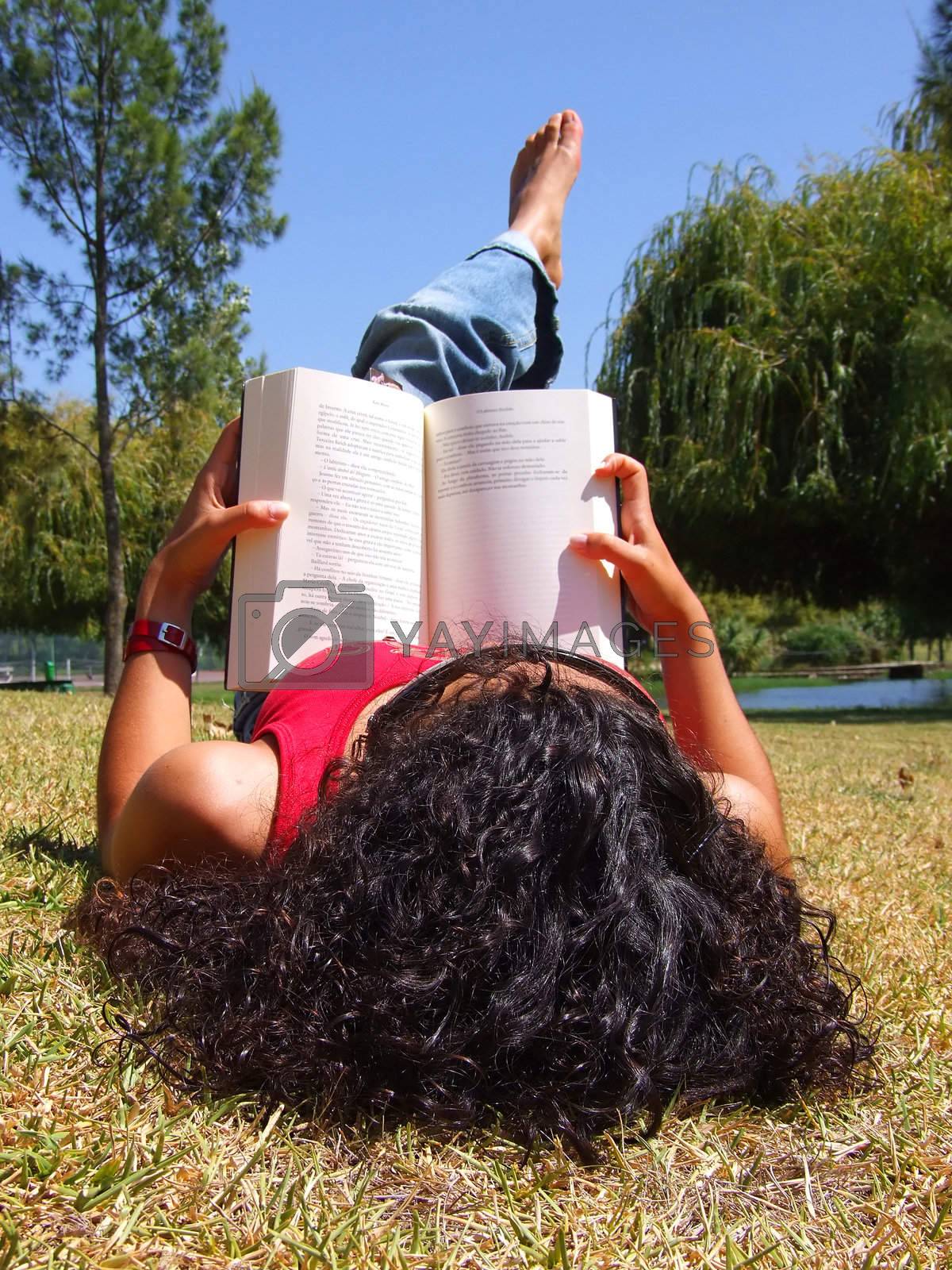 Royalty free image of Woman reading book in park by PauloResende