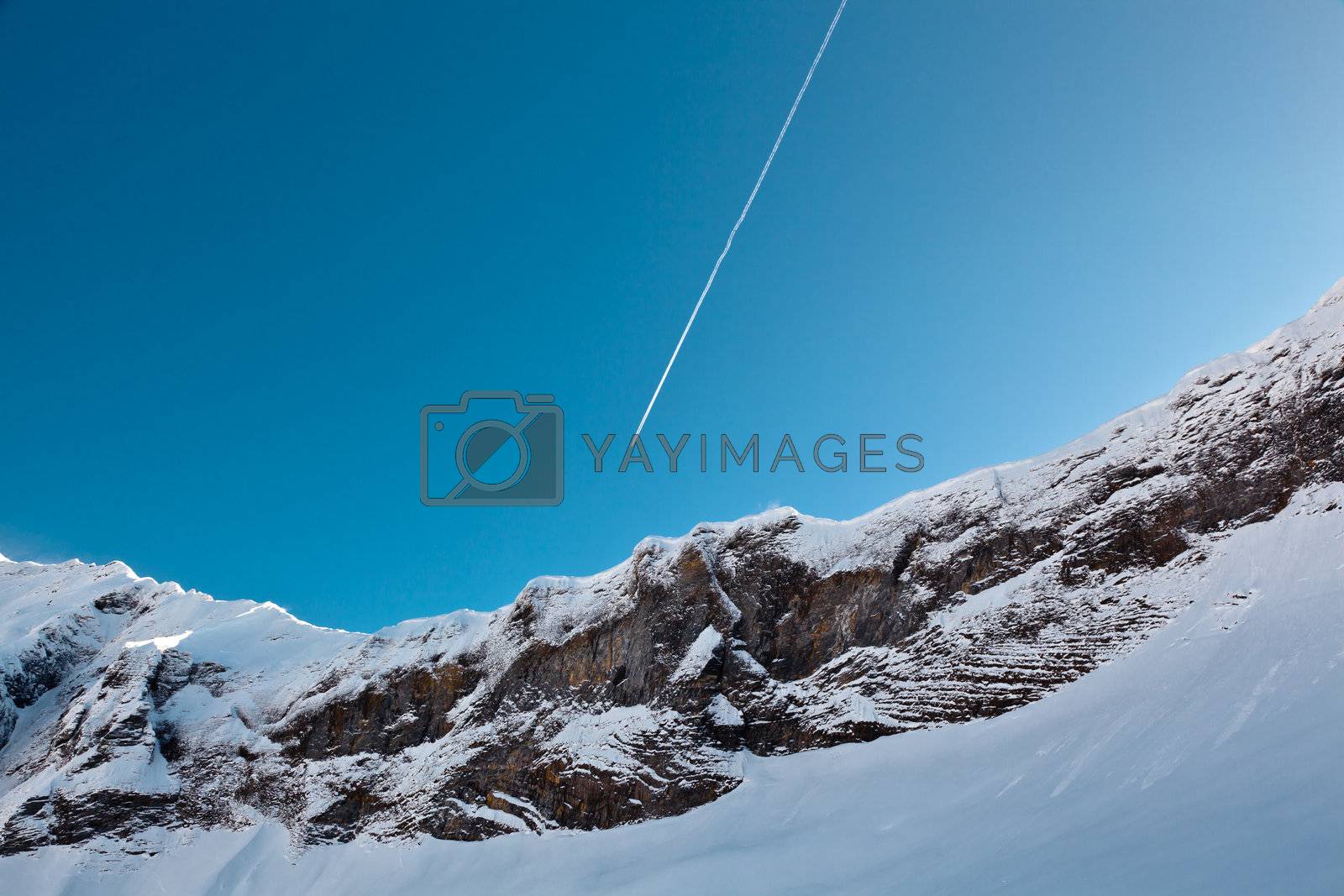 Royalty free image of Airplane Trail in Blue Sky above Mountain Peak, French Alps by anshar