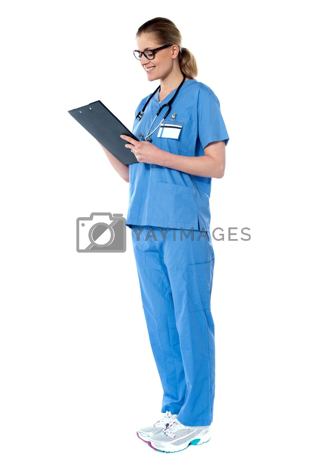 Royalty free image of Female surgeon with stethoscope, reading report by stockyimages