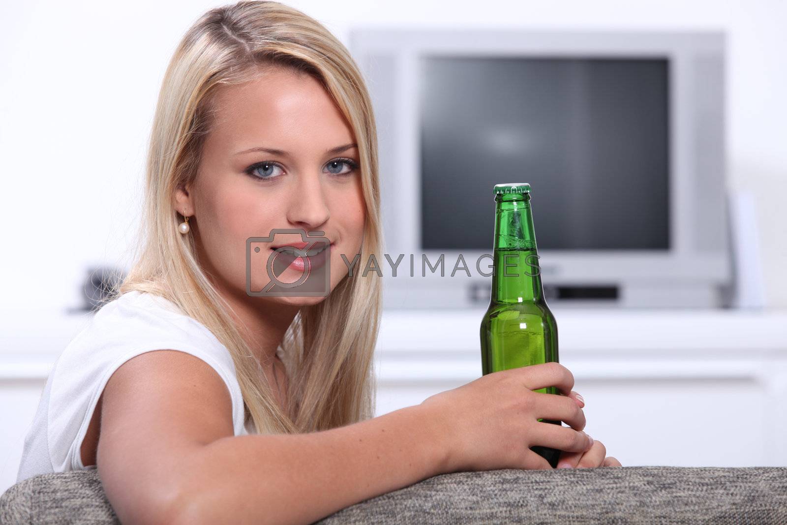 Royalty free image of Young woman at home with a bottle of unopened lager by phovoir