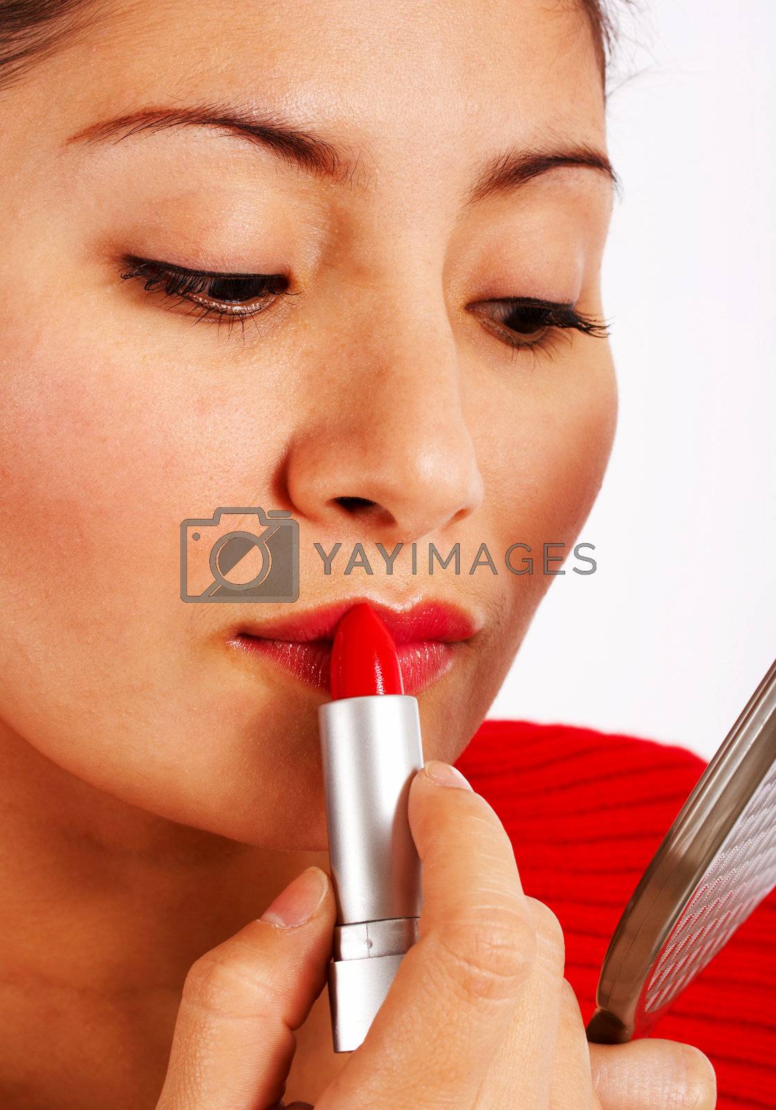 Woman Looking At In A Small Mirror And Applying Lipstick