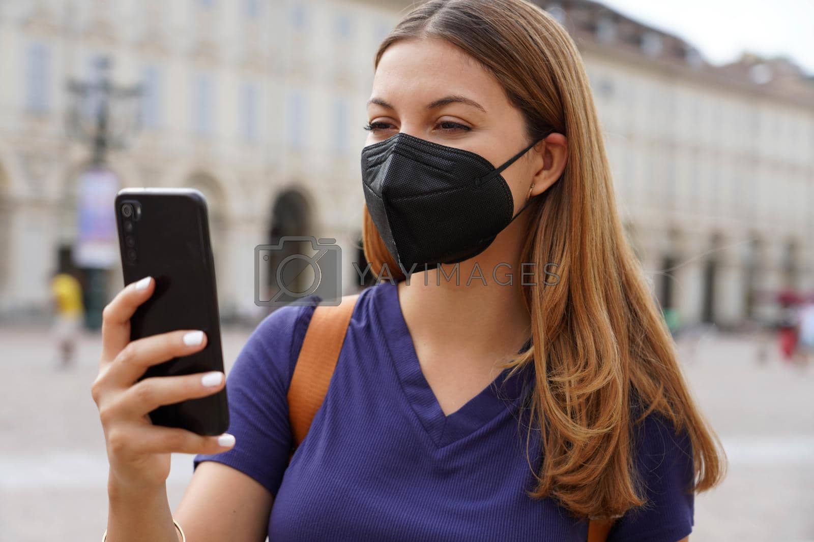 Royalty free image of Close up of girl with black protective mask FFP2 KN95 using smart phone with urban background by sergio_monti