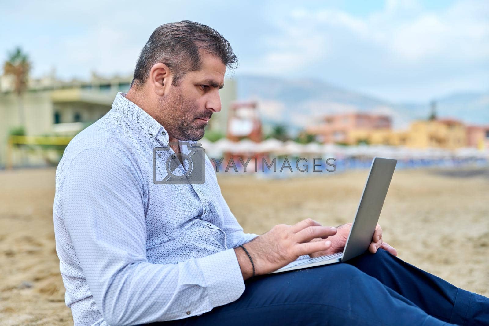 Royalty free image of Serious confident mature man with laptop outdoors by VH-studio