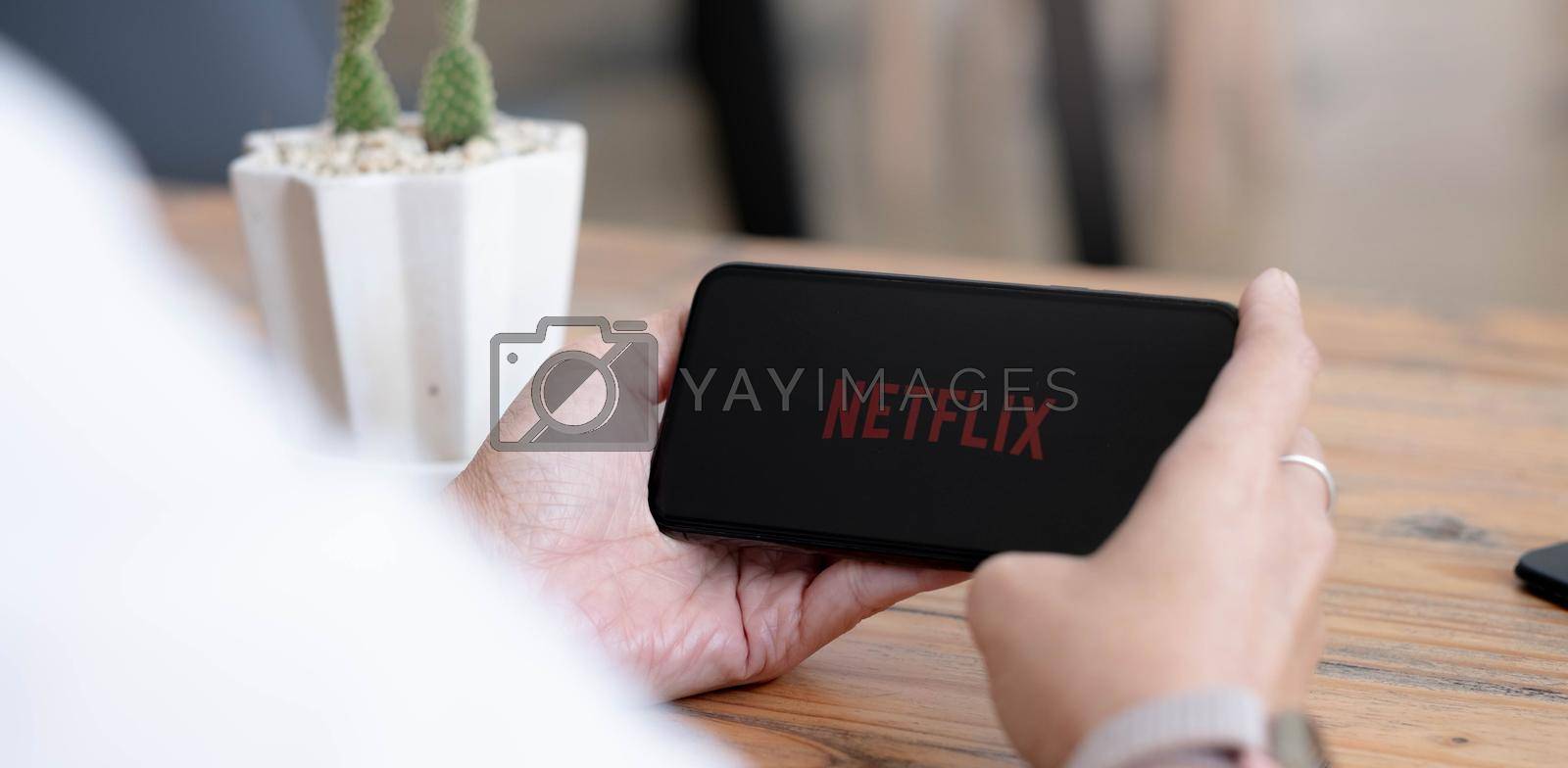 CHIANG MAI, THAILAND, AUG 2 2021 : Woman hand holding Smart Phone with Netflix logo on Apple iPhone Xs. Netflix is a global provider of streaming movies and TV series..