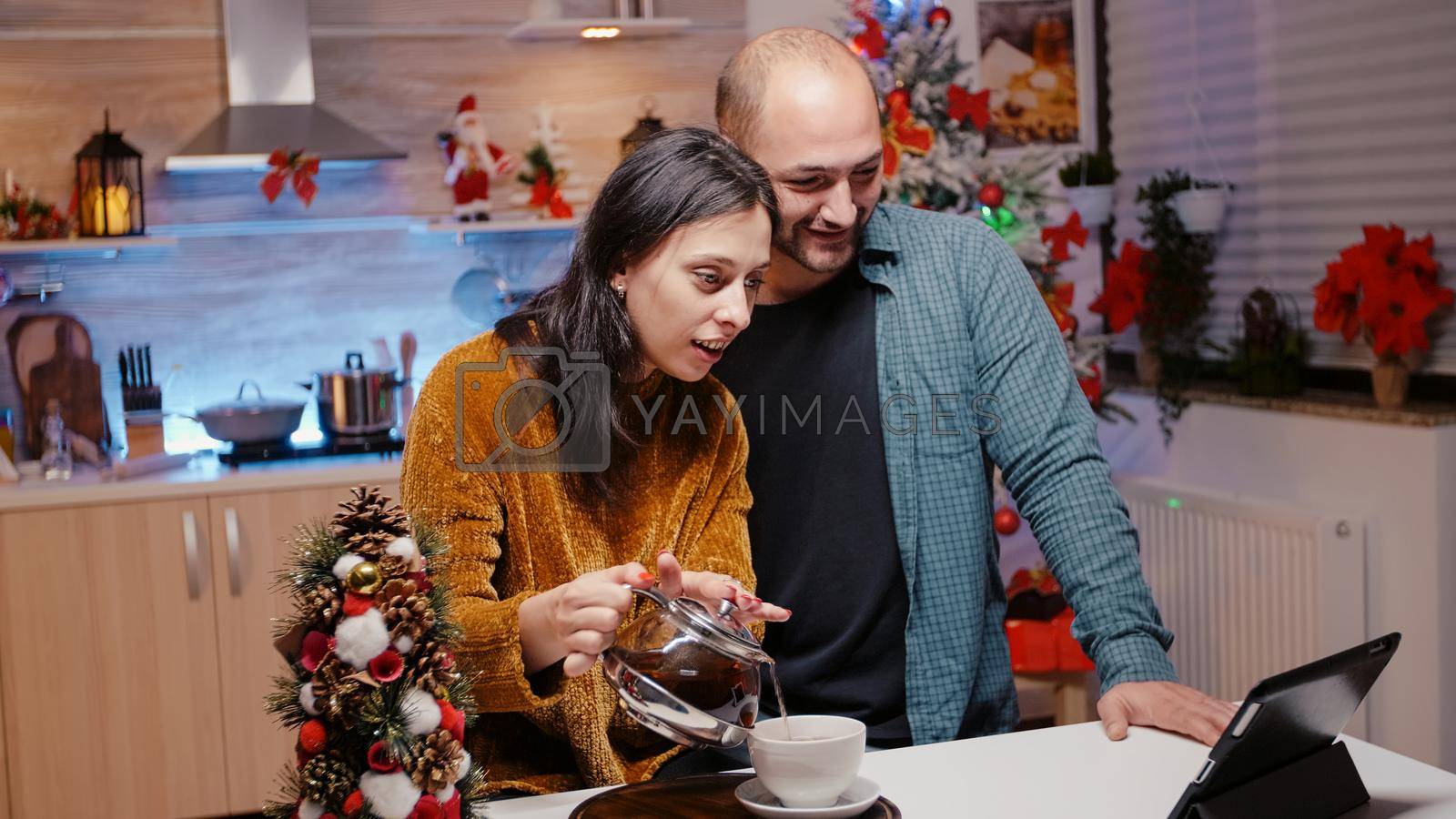 Couple using tablet for video call communication on christmas eve. Cheerful man and woman feeling festive while talking to family on online remote conference for holiday festivity.