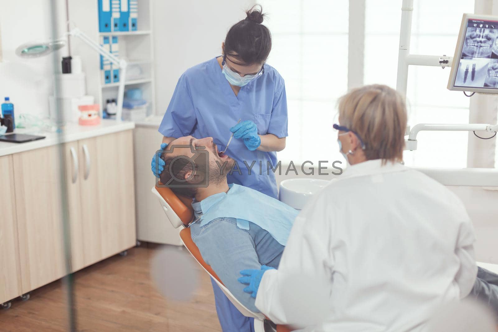 Royalty free image of Medical assistant analyzing mouth of sick patient preparing for dental surgery by DCStudio