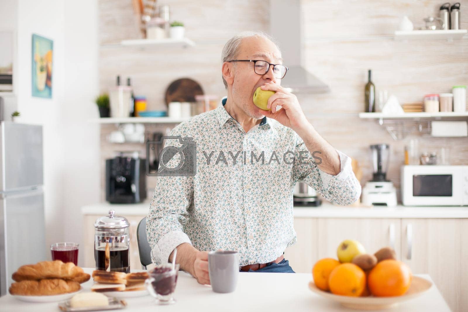 Royalty free image of Elderly man bitting green apple by DCStudio