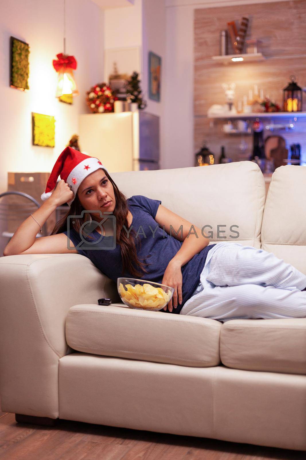 Royalty free image of Woman lying on sofa watching xmas movie on television during christmastime by DCStudio